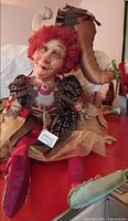 Full view of seated jester doll showing costume, tag, and overall appearance
