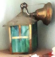 Overall view of brass hanging lantern with green stained glass panels and brass canopy