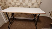 Full view of folding table with white top and black metal legs