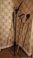 Group of six long-handled gardening tools leaning against wall