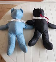 Light blue and black handmade cotton teddy bears lying face down on table