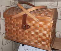 Exterior of woven wicker picnic basket with crossed handles and leather latch