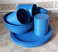 Stacked blue plastic mugs, bowls and plates