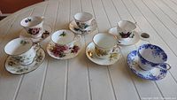 All seven teacup and saucer sets displayed on table