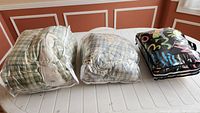 Three bagged twin duvets on table