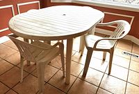 oval white vinyl patio table with two chairs in view