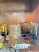 Amber wine glasses and ornate highballs on shelf