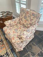 Front angle view of floral upholstered swivel armchair showing overall design