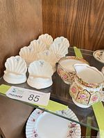 Creamer, sugar bowl and eight shell place card holders on glass shelf