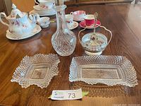 Full lot showing decanter, sugar bowl with spoon, square and rectangular pressed glass dishes