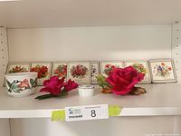 Shelf view showing two china roses, trinket box, planter, and eight floral coasters