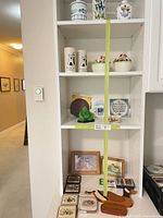 Overview of shelves showing canister, vase, cruet, tumblers, lidded bowls, Buddha, tiles, cards, signs, coasters, soap dish