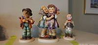 Four Hummel figurines on shelf