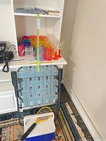 Overall lot showing folding chair, cooler, bug zapper and drinkware on shelving