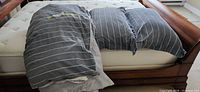 Duvet cover draped over mattress showing both dark and light grey sides plus two shams