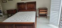 Front view of Ethan Allen queen sleigh bed with mattress, shows headboard and matching nightstands
