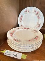 Stack of eight Royal Albert Lavender Rose dinner plates displayed on shelf