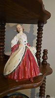 Front view of Royal Doulton figurine showing red skirt and white coat with black flecks