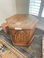 Full view of hexagonal wood side table with cabinet doors