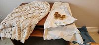 Folded crochet tablecloth and embroidered cloth with napkin rings on table
