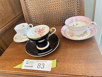 Three teacup and saucer sets displayed on wooden surface