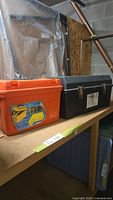 Orange and black plastic tool chests on shelf