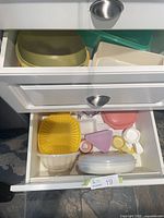 Open drawers showing multiple Tupperware bowls, lids and small containers