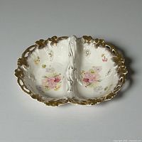 Overhead view showing divided porcelain dish, floral decoration, gold gilt rim, central handle