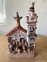 Front view of entire clay church sculpture with figures and clock tower