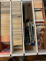 Top view of four-row storage box filled with sports trading cards and several sealed foil packs