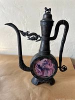 Front view of pewter ewer showing spout, dragon strut, painted glass panel, base, and lid finial