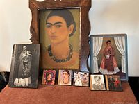 All eight items arranged: framed canvas portrait, two wood plaques, five small prints