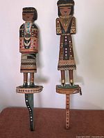Front view of both kachina dolls showing height, paint, clothing and bases