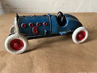 Left side view showing blue body, number 6, white wheels with red hubs, black driver