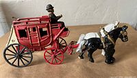 Side view of red stagecoach, driver, horses
