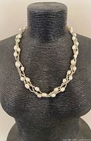 Necklace displayed on bust showing braided design and pearl spacing