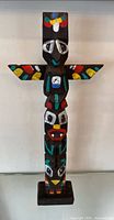 Full front view of multicolour carved totem pole on base