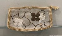 Front view of beaded clutch showing floral bead pattern and pearl trim