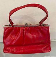 Front view of red patent leather frame purse with handle upright