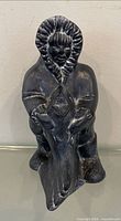 Front view of black ceramic Inuit figurine holding fish