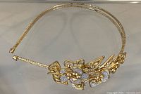 Full view of gold-tone metal headband with floral embellishment