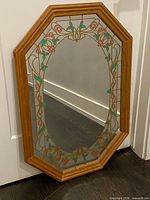 Front view of octagonal wood framed mirror showing stained glass floral border