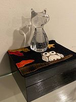 Glass owl figurine on top of black jewelry box with felt owl and leaves