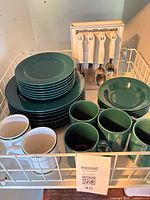 Overall lot showing green dinnerware stacks, mugs, utensil stand