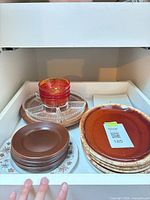 Overview of stacked plates, saucers, bowls and divided relish tray inside cabinet
