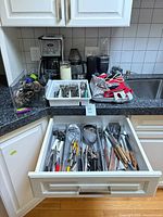 Drawer open showing assorted stainless utensils and flatware