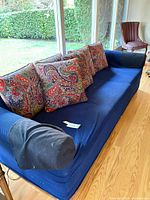 Front view of blue slipcovered sofa with paisley pillows