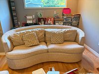 Front view of curved beige sofa with two pillows