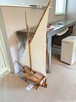 Full view of wooden sailboat model standing on floor
