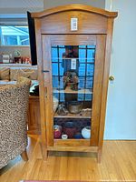 Full front view of cabinet showing arched top and glass door